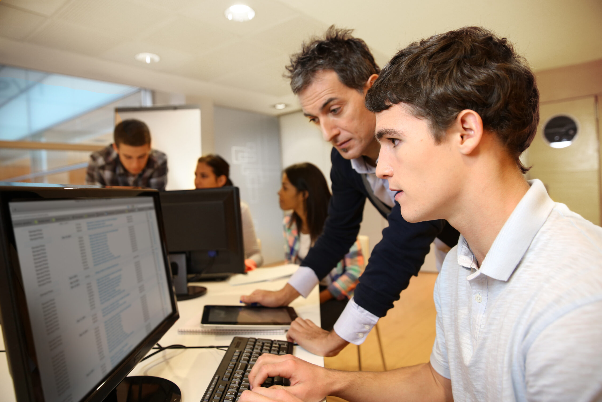 Adult man helping student in classroom